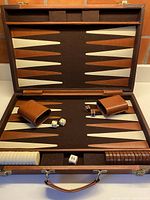 Open backgammon set showing board, checkers, dice cups, dice, doubling cube