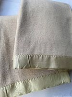Both butter cream wool blankets with satin binding folded