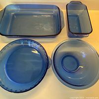 Top view of all four sapphire blue Pyrex pieces: rectangular baker, loaf pan, pie plate, mixing bowl