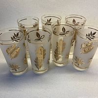 Front view of all seven Libbey frosted tumblers showing gold leaf design