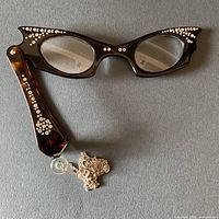 Full view of folded-out Bakelite lorgnette eyeglasses with attached chain showing rhinestone accents