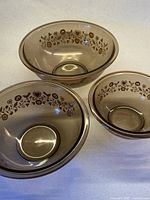 All three smoky brown Pyrex nesting bowls stacked to show size range and exterior motif