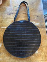 Front view of round vegan leather handbag with reptile embossing