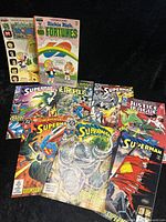 Overview of seven Superman comics and two Richie Rich comics arranged on black background.