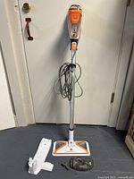 Full view of Bissell PowerFresh Slim steam mop with handle, power cord wrapped, base head on floor, plus accessories and storage piece beside it.