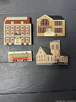 Five Cat's Meow Village wooden buildings arranged on a flat surface showing all miniatures in the lot with visible black cat figurines integrated into window and roof details.