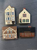 Four Cats Meow wooden collectible buildings arranged in two rows, showing various architectural styles and black cat figurines.