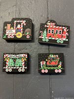 Four wooden collectible pieces from Cat’s Meow Village’s Candy Cane Express Train showing locomotive, passenger cars and sleigh car with Christmas decorations and hidden black cats