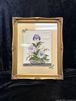 Full view of framed crewelwork pansy embroidery with ornate gold-tone frame and fabric mat featuring embroidered ivy leaves.