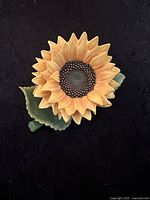 Front view of Lenox sunflower porcelain figurine showing detailed yellow petals and textured center with green leaves underneath.