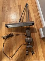 Full view of the bronze architect desk lamp showing the adjustable arm, rectangular lamp shade, power cord, and clamp base.