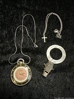 Full view of all three items - pendant watch on chain, small cross necklace, whistle pendant with ring.