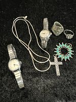 Photo shows the entire lot laid out on black cloth, displaying two watches, chain, three rings, and two pendants.