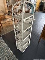 Full angled view of the tall white wicker shelf showing all five shelves and flower pattern design on side.