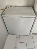 Front view of white Insignia chest freezer with closed lid and inset handle on the front.