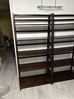 Front view of the dark brown ladder shelving unit showing all six shelves and ladder-style design.