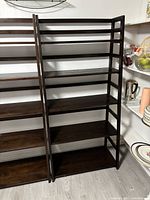 Front view of dark brown wooden ladder shelving unit with 6 shelves showing open shelving and frame details.