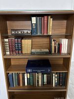 Books on wooden bookshelf with antique and vintage volumes, including Shakespeare and poetry collections.