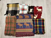 Seven blankets laid out showing variety of patterns and colors