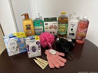 Photo of the lot showing multiple health and beauty products, cleaning products including Pine-Sol, mouthwash, shampoo, lotions, Febreze air fresheners, bath accessories, hairdryer, and small tubes of hair product.
