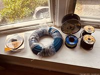 Photo showing various spools of wiring cords including a large blue coil, and smaller black wire spools.