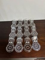 Twelve transparent plastic teacup and saucer display stands arranged in four rows of three each, showing the overall lot quantity and uniformity.