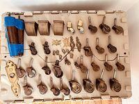 Large assortment of vintage brass and wood casters and brass hardware parts organized on a plastic surface.