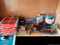 Wide shot of the lot showing window insulation kits, hammer, small tools and accessories on a shelf.