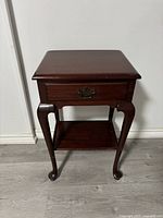 Front view of the wooden nightstand showing drawer and curved legs