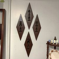 Front view of all 4 diamond-shaped wooden wall hangings arranged vertically on a wall, showing carved chess pieces knight, pawn, rook, and king.
