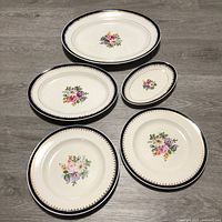Five vintage Swinnertons plates arranged on floor, showing floral center design, blue rim, and gold trim.