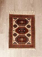 Top view of the small rectangular vintage rug showing geometric medallion and detailed border pattern with fringes on both shorter ends.