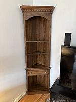 Full view of the vintage corner display cabinet showing shelves, compartments, and faux drawer.