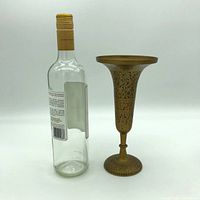Photo showing the vintage solid brass etched vase next to a standard wine bottle for scale, highlighting the vase's height (~9 inches) and detailed etching.