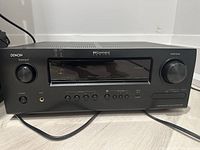 Front view of Denon AVR-2112CI home theatre receiver showing power button, headphone jack, source select and volume knobs, and control buttons.