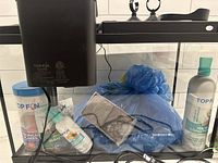 Top Fin branded water conditioner bottle, tropical flakes fish food, algae remover, and wrapped fish net in the fish tank