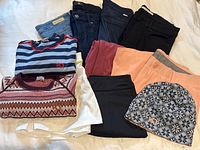 Photo showing four pairs of women's jeans folded and lined up, from brands AG, Mother, 7 for All Mankind, Fidelity, plus wool long sleeve tops and hat.