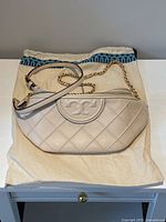 Bag on cream dust bag, front view showing quilting and strap placement