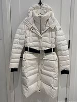 Front view of white quilted parka hung on hanger