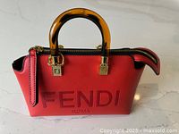 Front angled view of red leather bag showing ‘FENDI ROMA’ embossing, tortoiseshell acrylic handles and gold-tone zipper pull