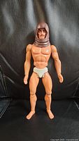 Front view of the 1971 Mattel Big Jim Zorak figure with angry human face and brown hood, standing upright on black leather.