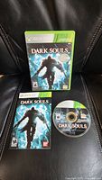 Front view of Dark Souls Xbox 360 game case, manual, and disc showed on a black surface