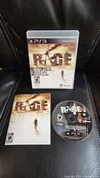 Front view of the Rage Anarchy Edition PS3 game case, disc, and manual displayed together on a black leather surface.