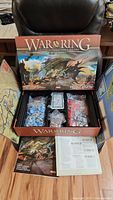 Game box exterior and components inside with miniatures, cards, tokens, die, and rulebooks.