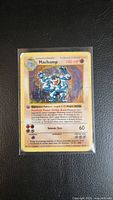 Photo of front view of 1999 1st Edition Pokemon Machamp holographic card showing the full card and condition with worn edges and surface.