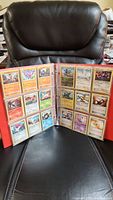 Two-page red binder displaying Pokemon cards in plastic sleeves, featuring various Pokemon with colorful artwork.