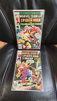 Photo showing two Marvel Team-Up comic books in protective sleeves, upright on a black surface.