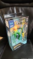 Sealed box of deluxe Aquaman figure with trident and smaller accompanying character figure visible through the window packaging.