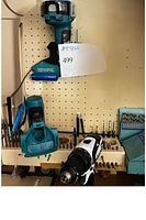 Four cordless drills, battery chargers, and various drill bits on a pegboard and wooden surface.