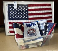 Framed American flag with three sealed 3 x 5 feet flags in plastic bin below.